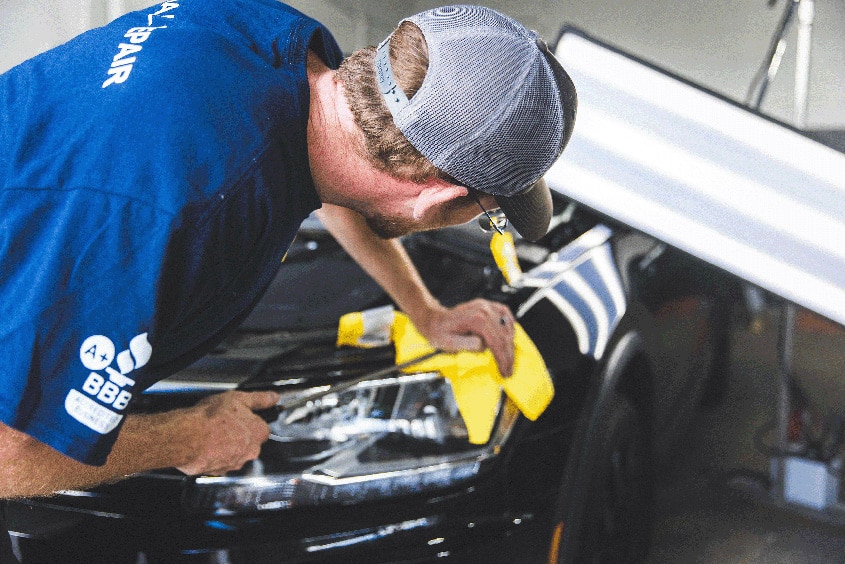 Mechanic pulling out a dent from a car with hail damage